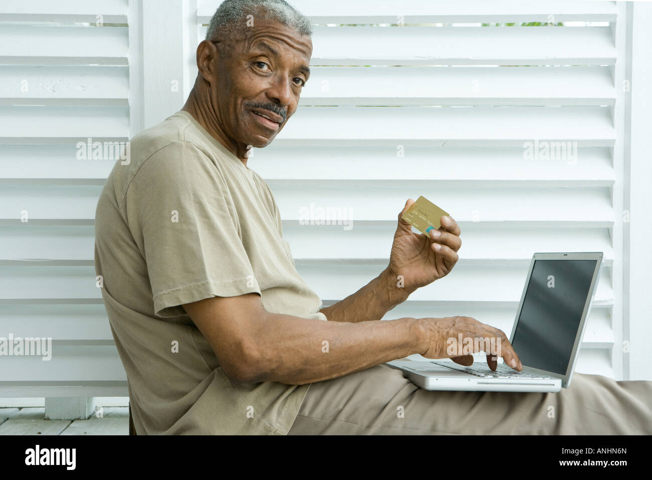 Senior man making credit card purchase online, smiling at camera Stock Photo