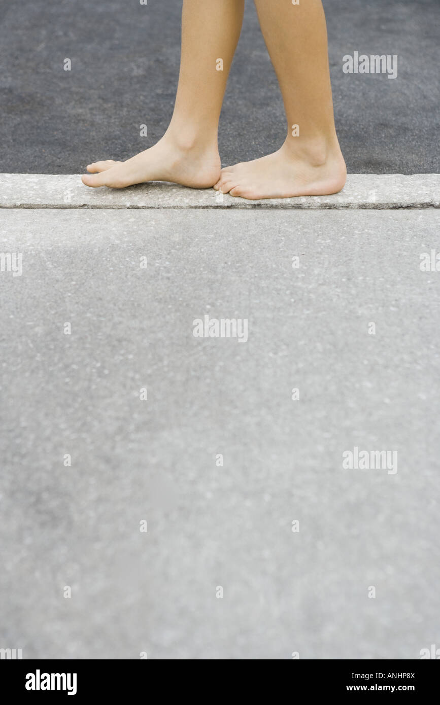 Child walking along crack in sidewalk, cropped view of feet Stock Photo