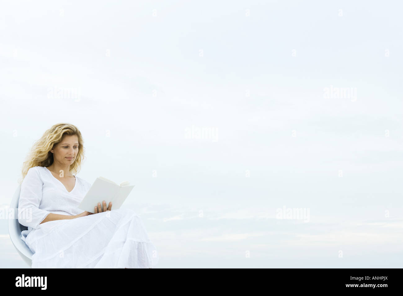 Woman sitting in chair outdoors, reading book Stock Photo Alamy