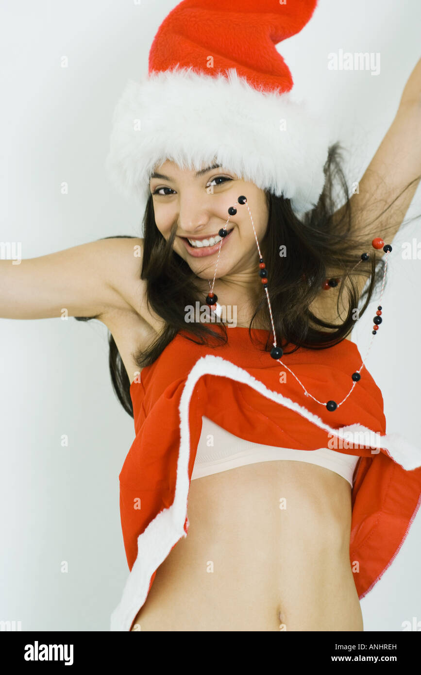 Teenage girl in Santa hat jumping, smiling at camera, midriff exposed Stock Photo