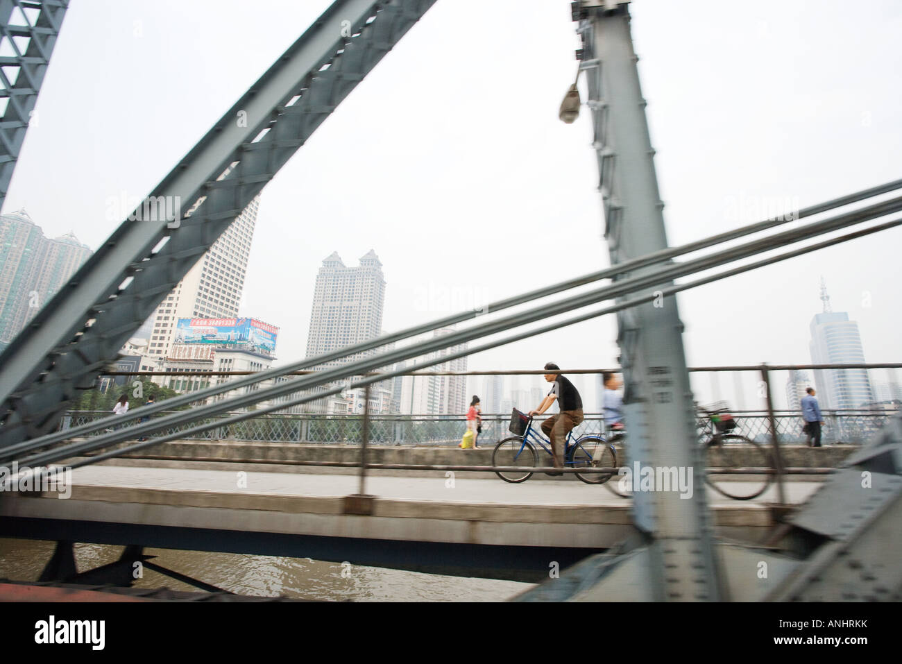 Cyclists and pedestrians on footbridge, cityscape in background Stock Photo