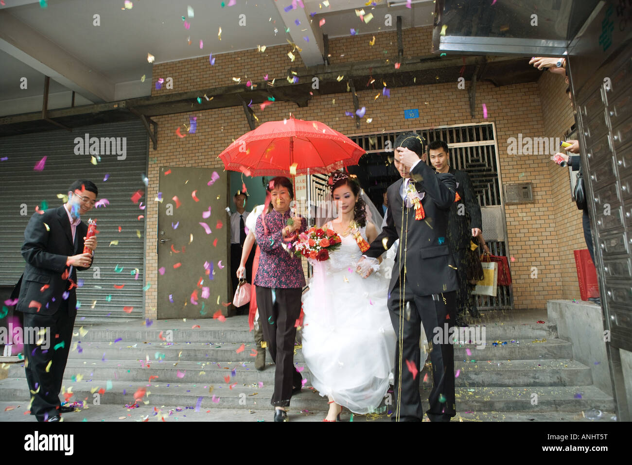 Chinese wedding, bride and groom leaving under confetti, bride covered