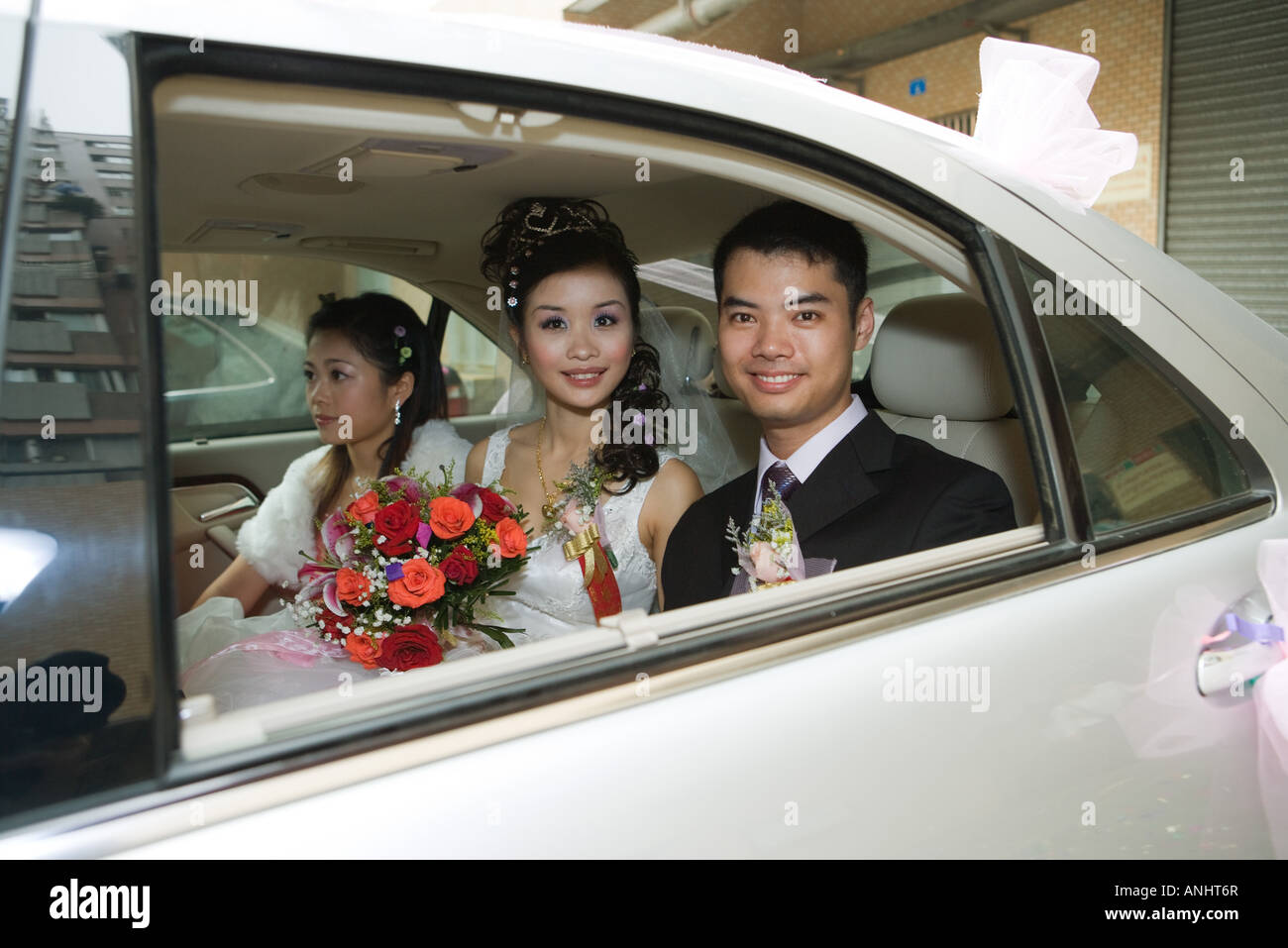 Bride and groom in car with bridesmaid, smiling at camera Stock Photo ...