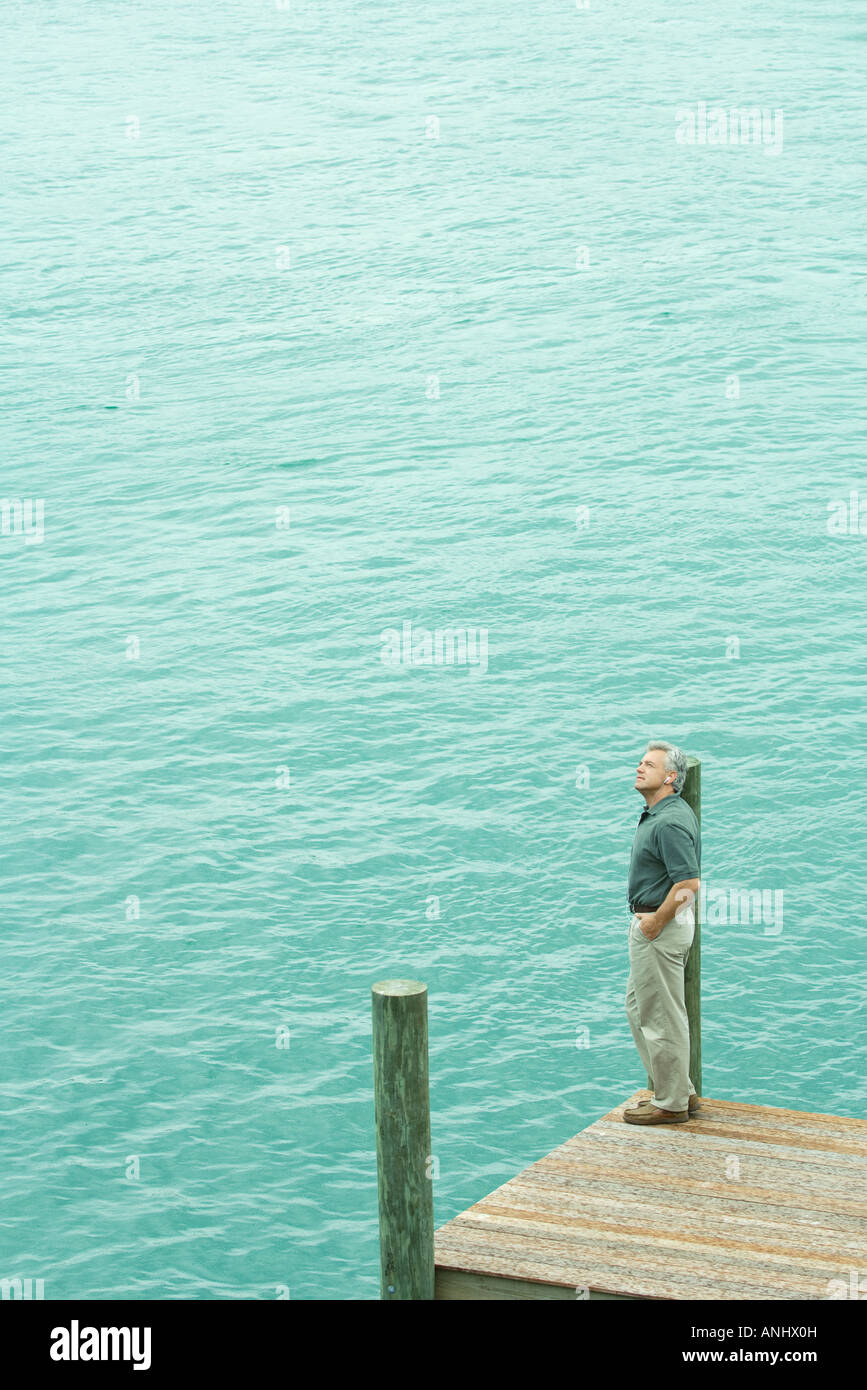 Man standing next to water listening to earphones, looking up, high angle view Stock Photo