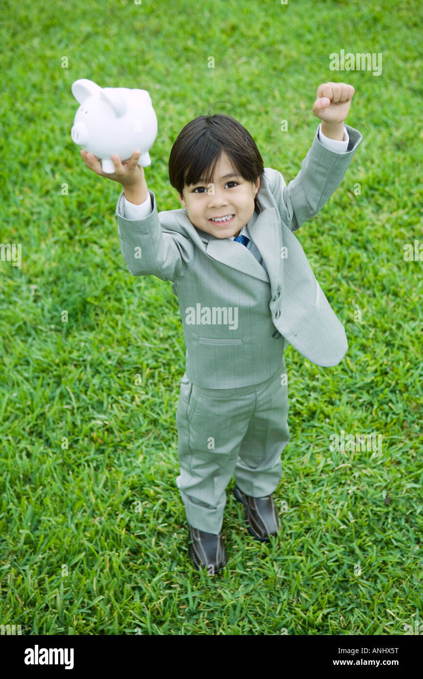 Little boy dressed in full suit holding up piggy bank Stock Photo - Alamy