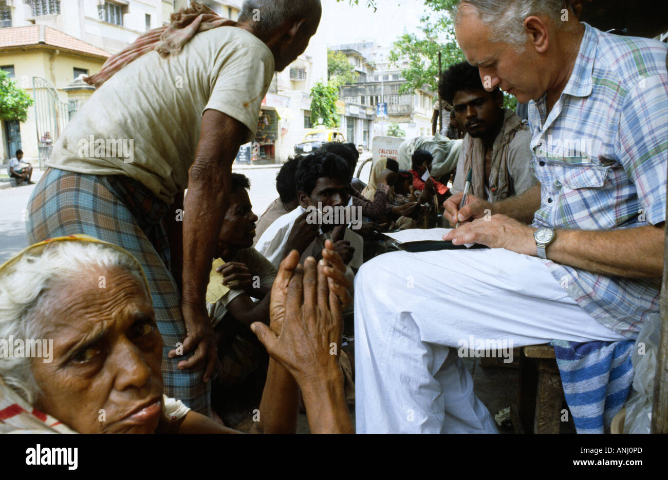 Dr. Jack Preger, founder of NGO Calcutta Rescue, treating slum dwellers on the streets of Kolkata, the only free healthcare available to them. India Stock Photo