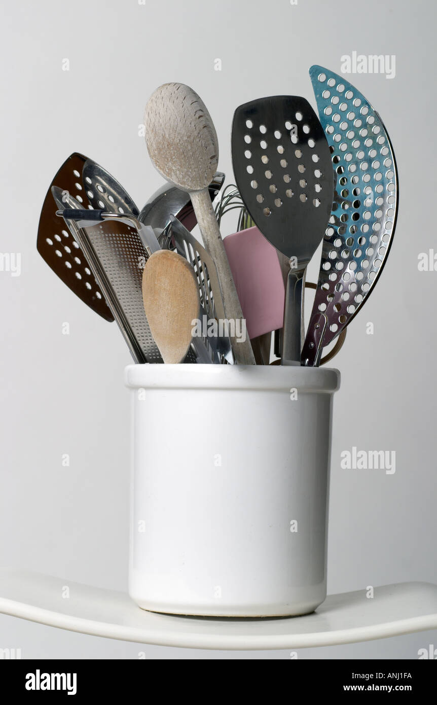kitchen utensils in a white pottery cylinder against a white background ...