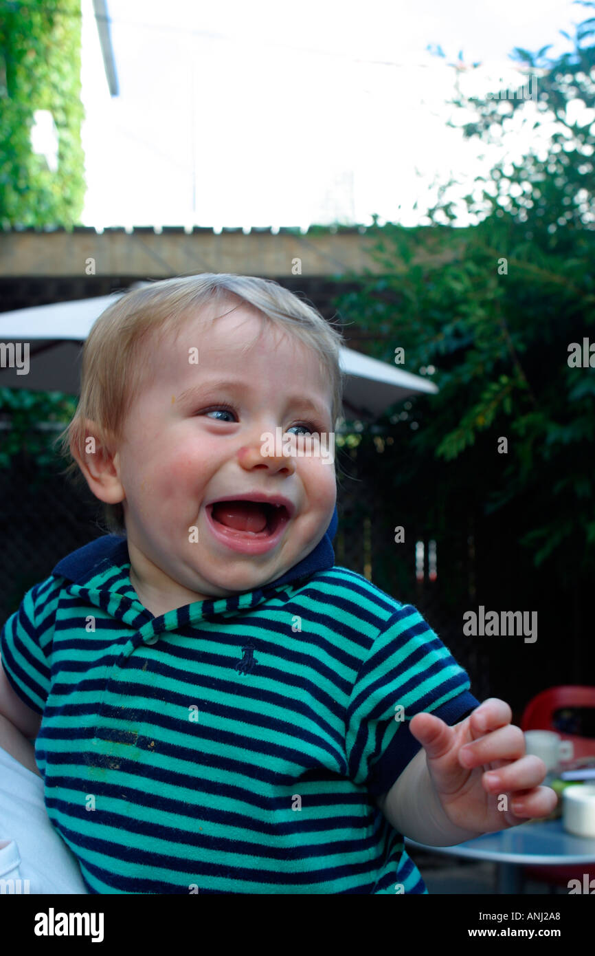 Happy toddler laughs in back yard with mother Model released and Property released Image youth youthful young one ones America Stock Photo