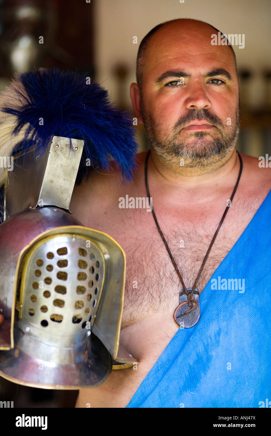 A reenactor dressed as a Roman age Gladiator poses with a helmet, Chedworth Villa, Gloucestershire, UK Stock Photo
