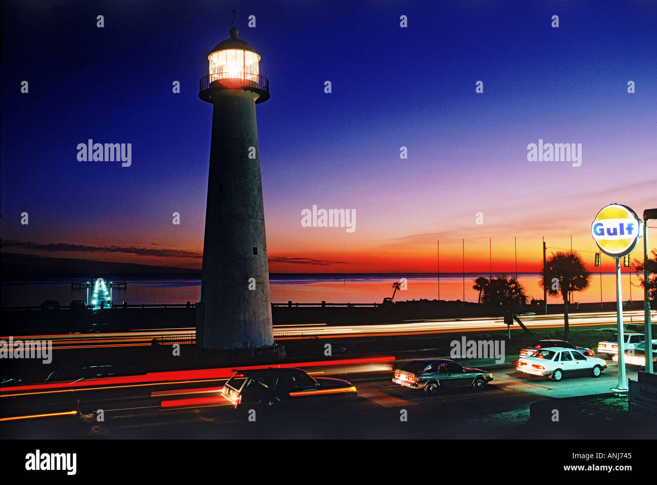 The Old Biloxi Lighthouse on Gulf of Mexico in Mississippi with passing traffic at dusk Stock Photo