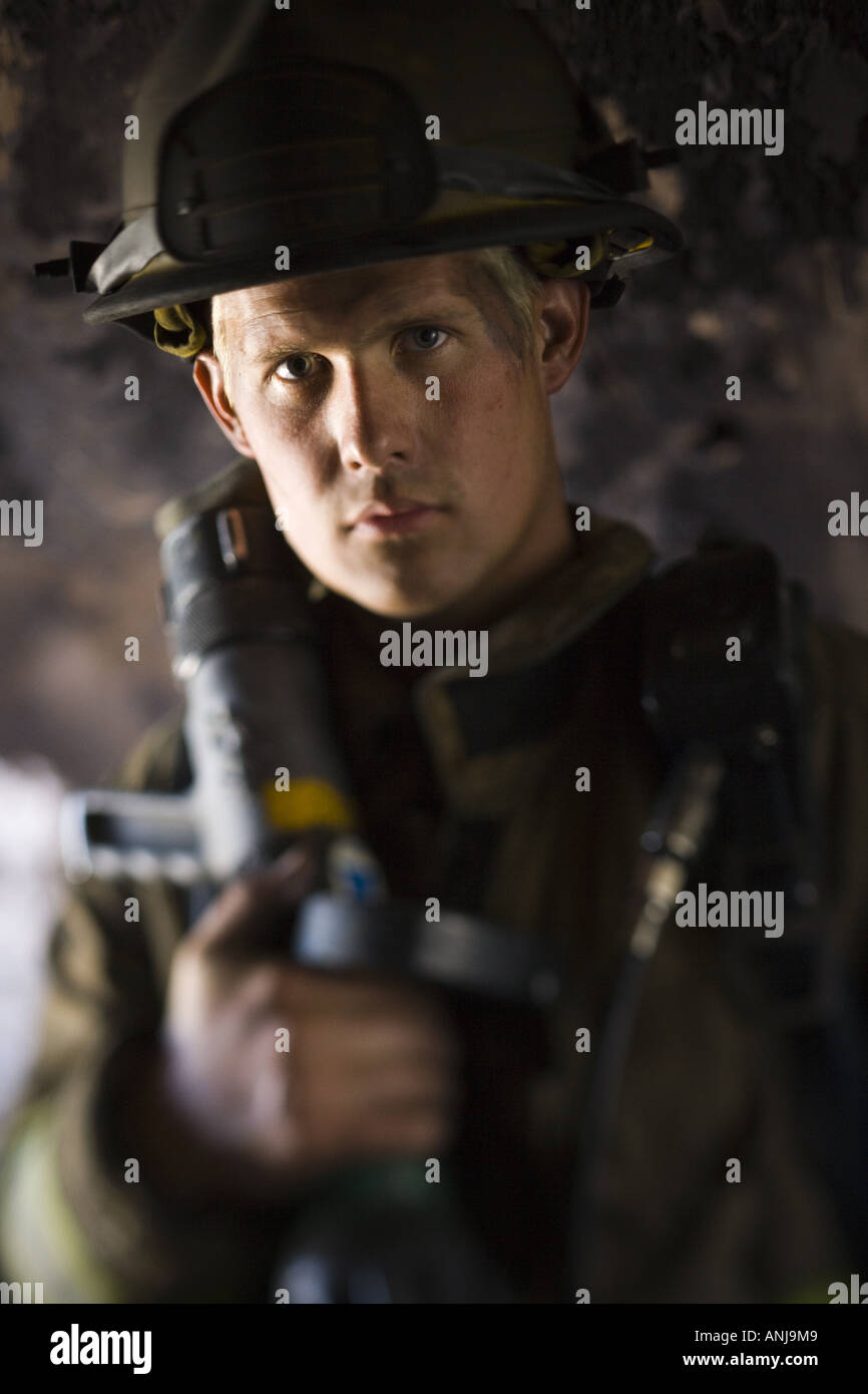 Portrait of a firefighter holding a hose Stock Photo