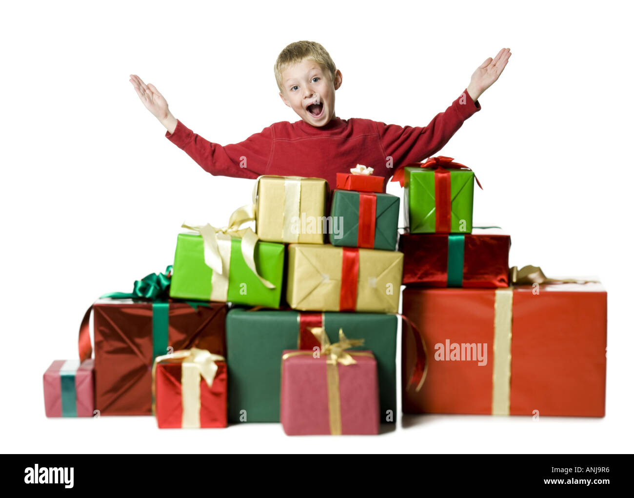Portrait of a boy standing with his arms raised with gifts around him Stock Photo
