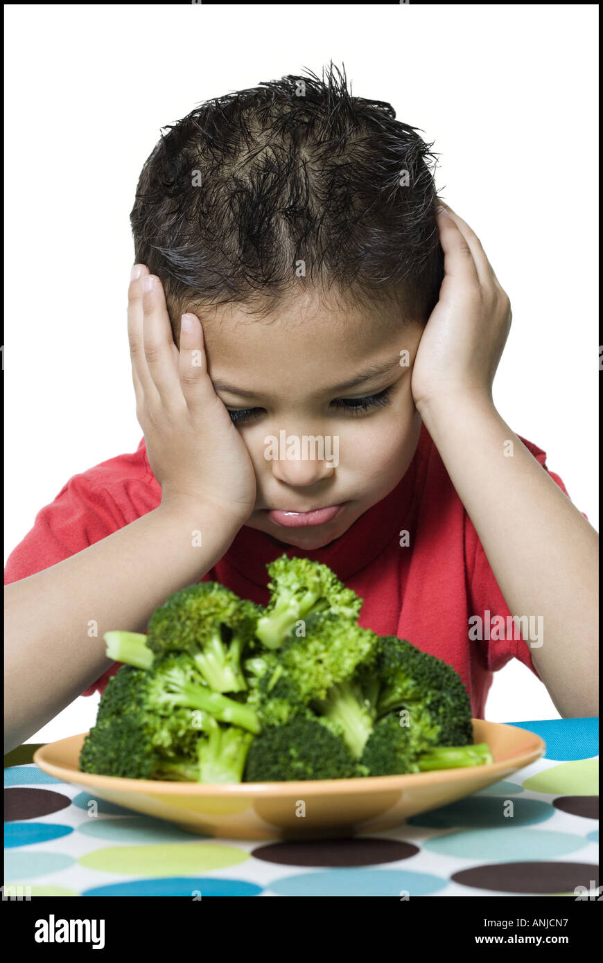 Close up of a boy looking at broccoli in a plate Stock Photo