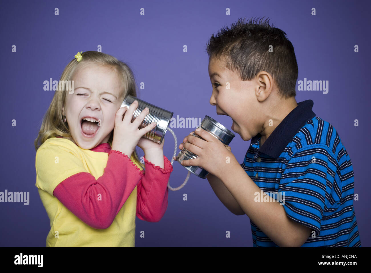 Boy and a girl playing with a tin can phone Stock Photo