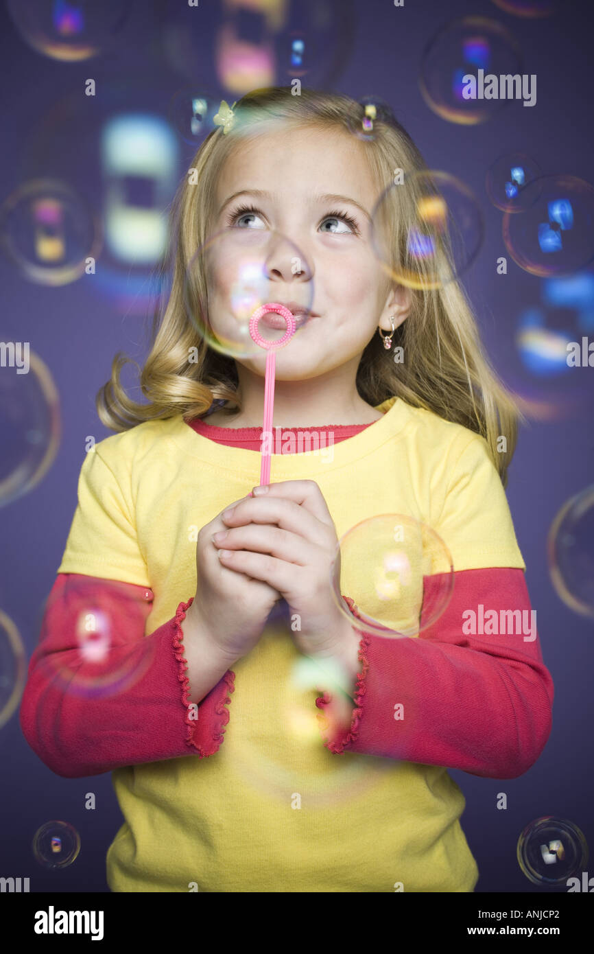 Close up of a girl blowing bubbles with a bubble wand Stock Photo