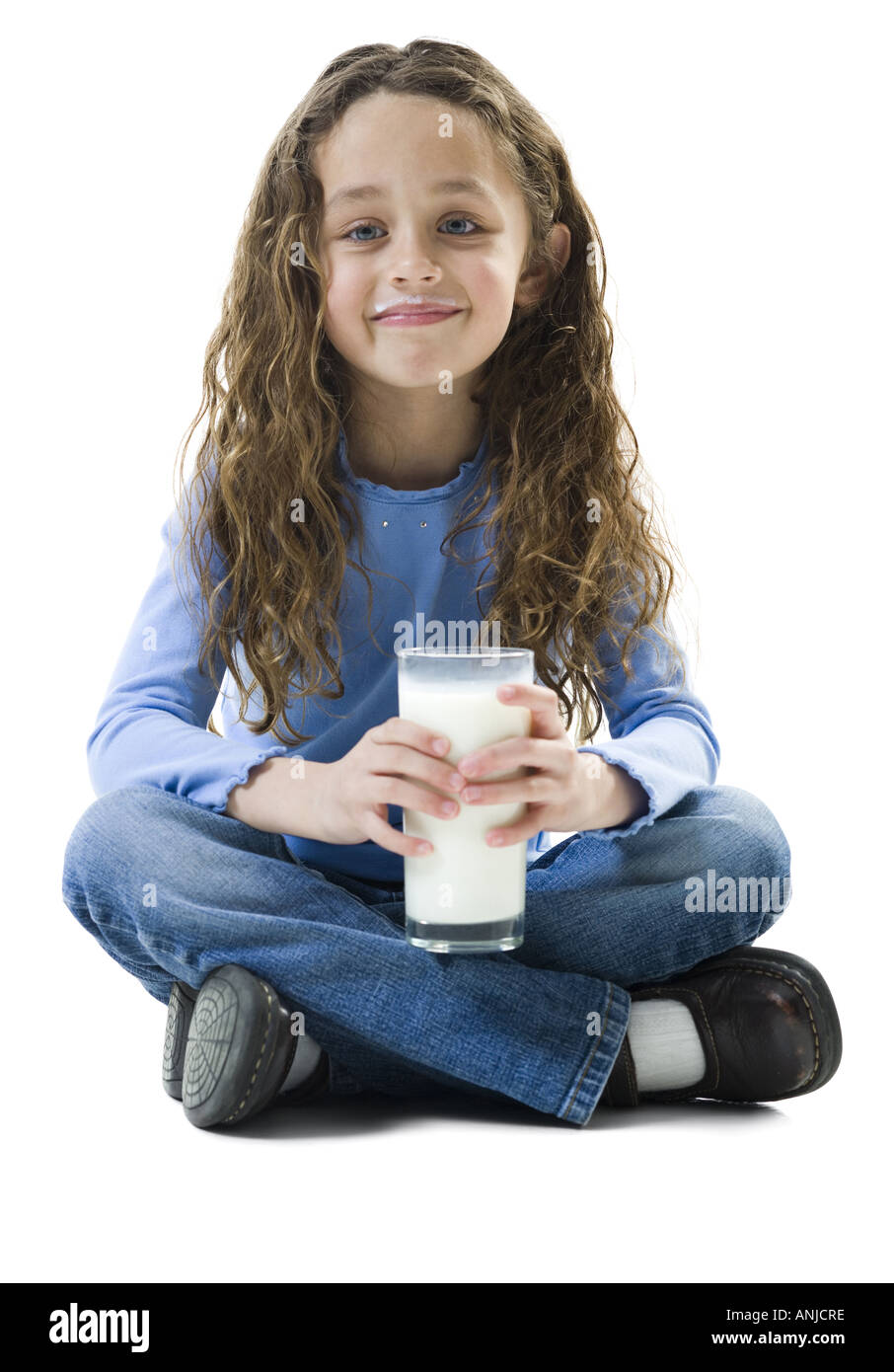 Portrait of a girl sitting on the floor and holding a glass of milk Stock Photo