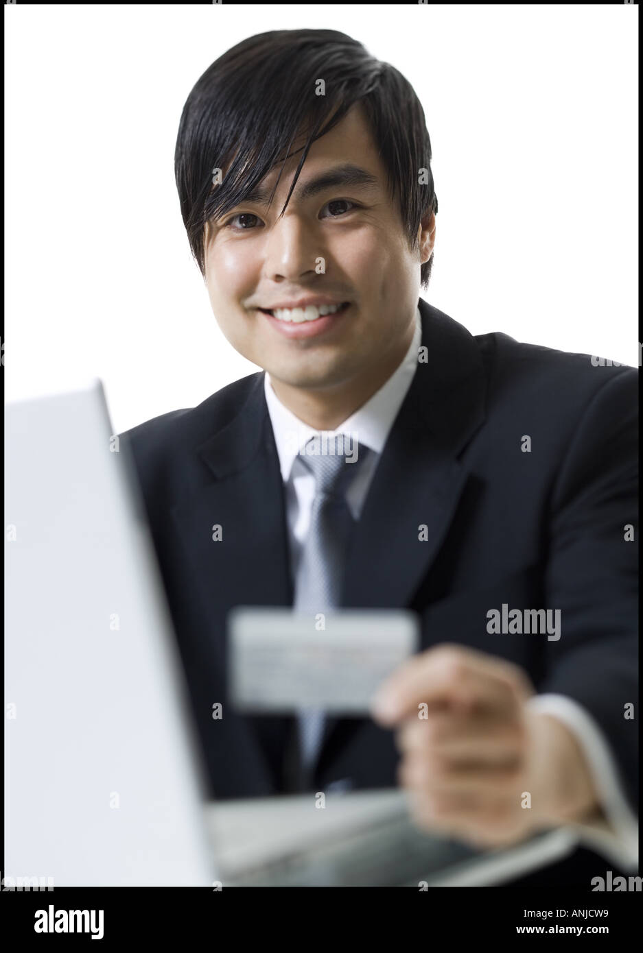 Close up of a businessman sitting in front of a laptop and holding a credit card Stock Photo