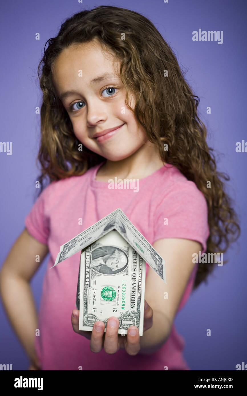 Portrait of a girl holding a house made of American dollar bills Stock Photo