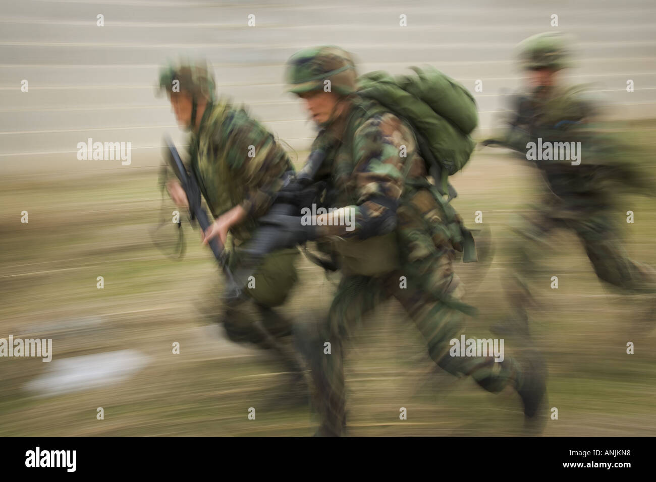 Side profile of three soldiers running on a field Stock Photo
