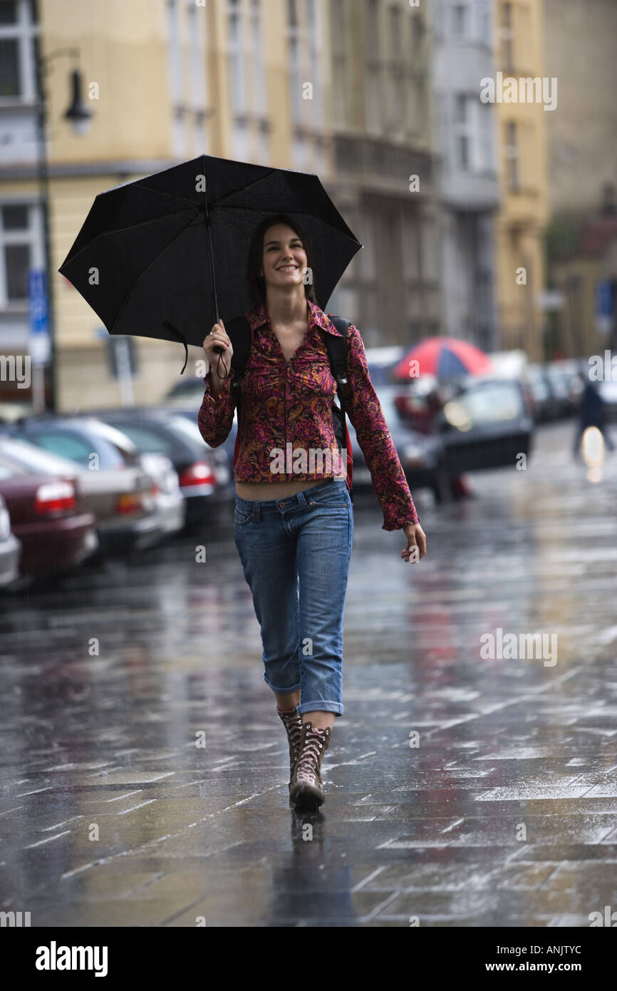 Teenage girl walking in the rain with an umbrella Stock Photo - Alamy