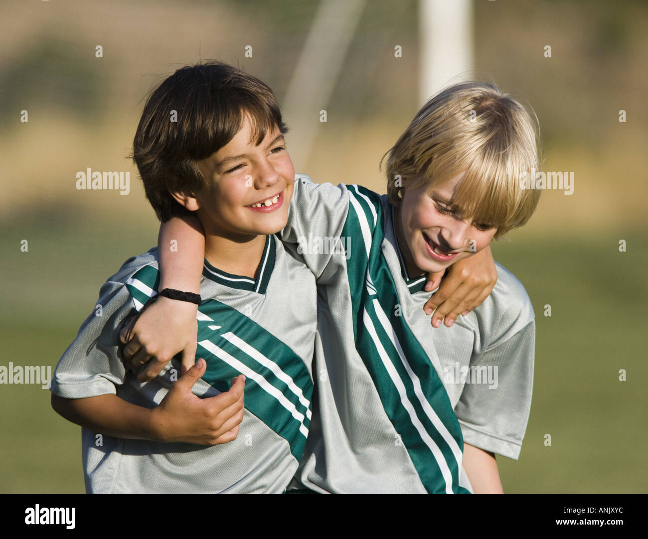Two boys in soccer uniforms with arms around each other Stock Photo - Alamy