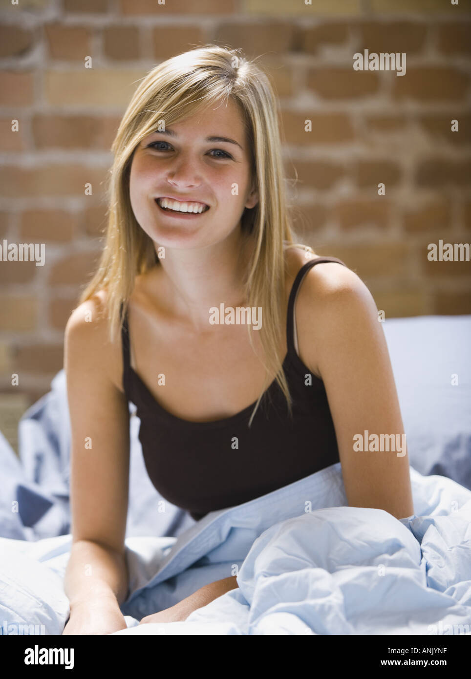 Portrait of a young woman sitting on a bed Stock Photo - Alamy