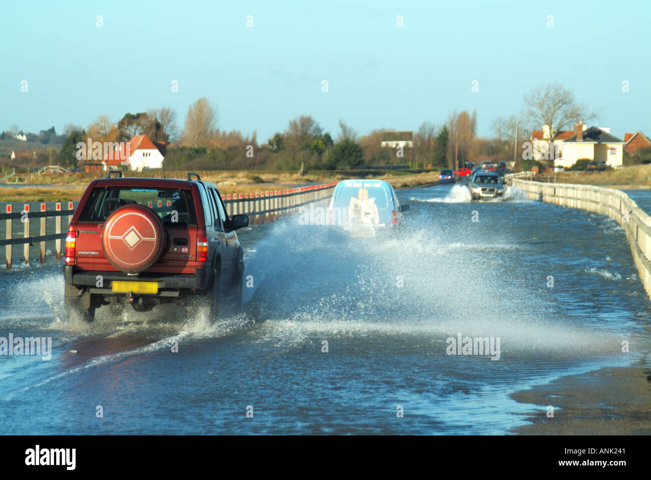 Cars drive in high tide covering vehicle causeway which is the only road link to Essex UK mainland with the island of East and the town of West Mersea Stock Photo