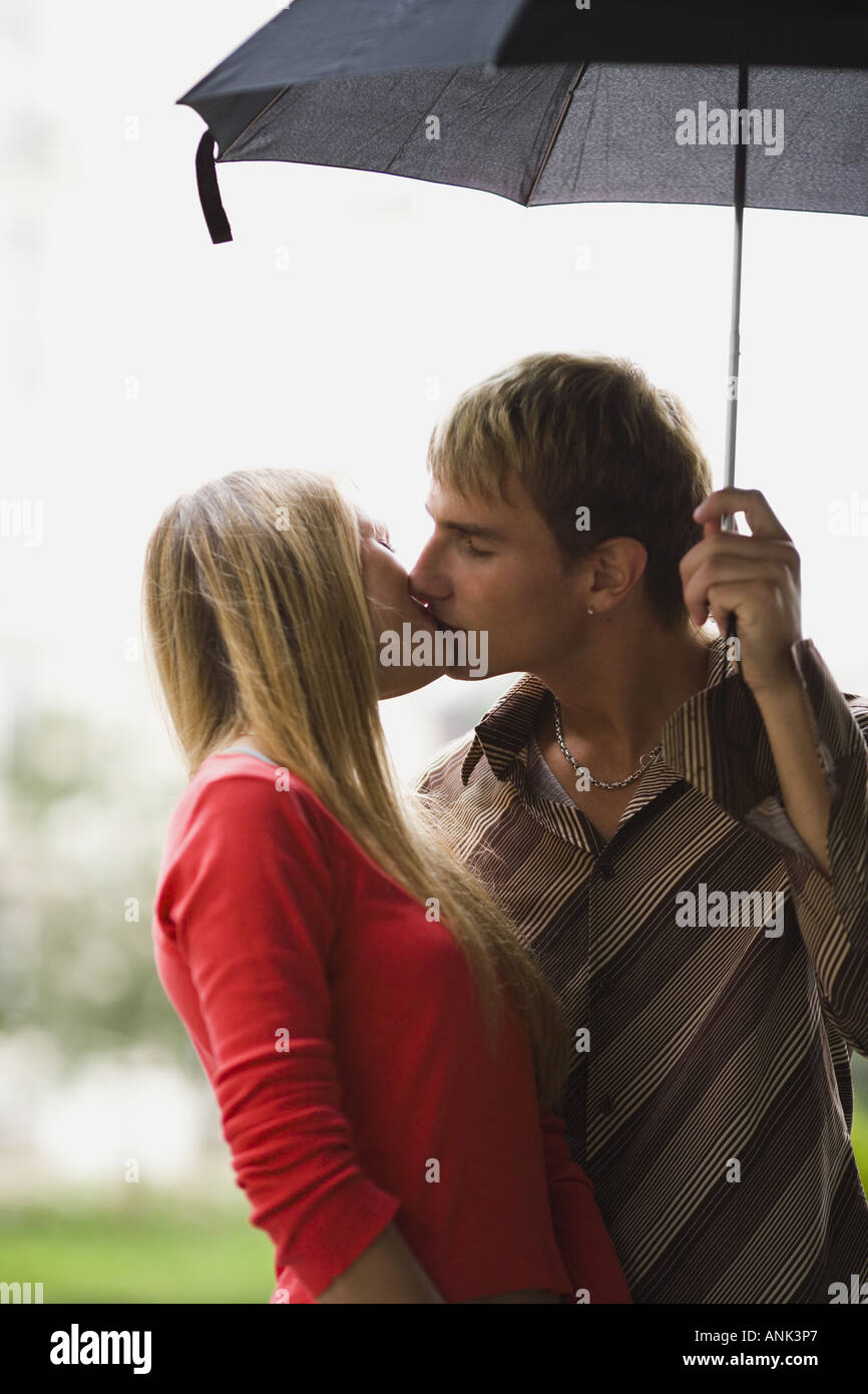 Teenage couple kissing under an umbrella Stock Photo Alamy