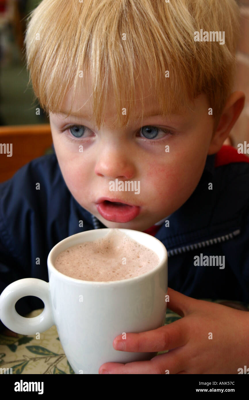 3 year old boy drinking mug of hot chocolate in a cafe Stock Photo - Alamy