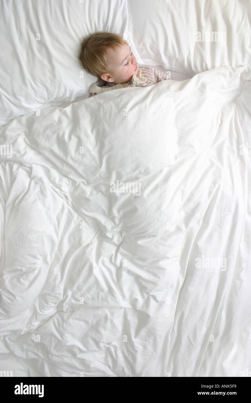 18 month old girl asleep in a bed with duvet Stock Photo Alamy