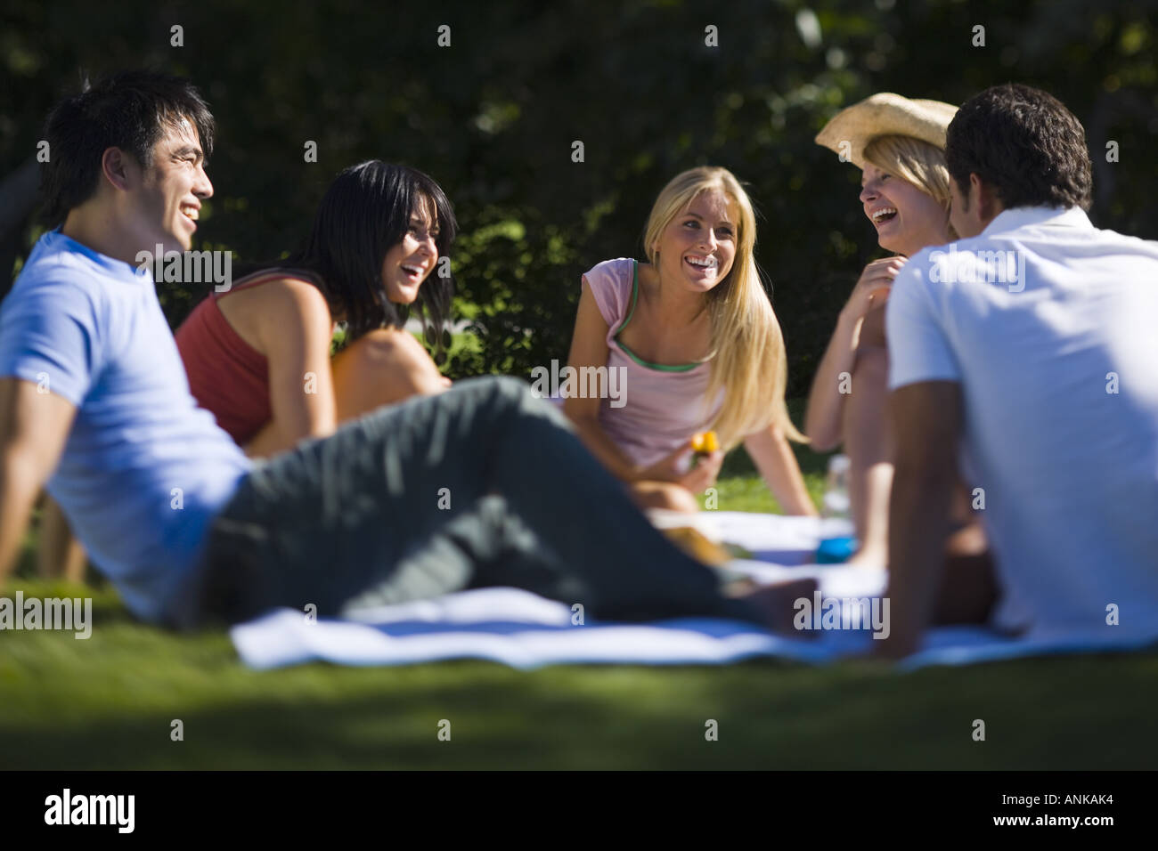 Four young people sitting in a park Stock Photo - Alamy