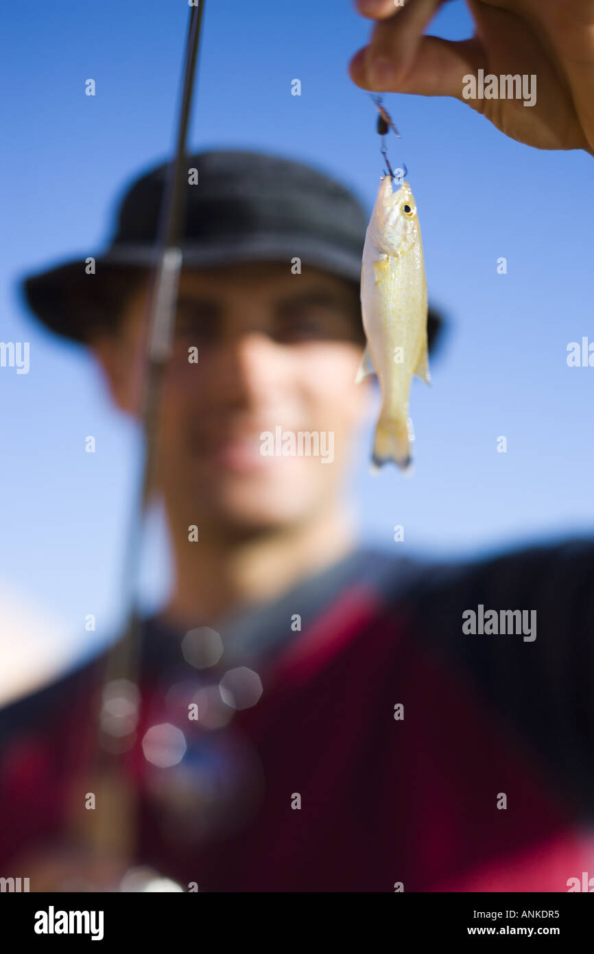 Young man holding a fishing bait with a fishing pole Stock Photo - Alamy
