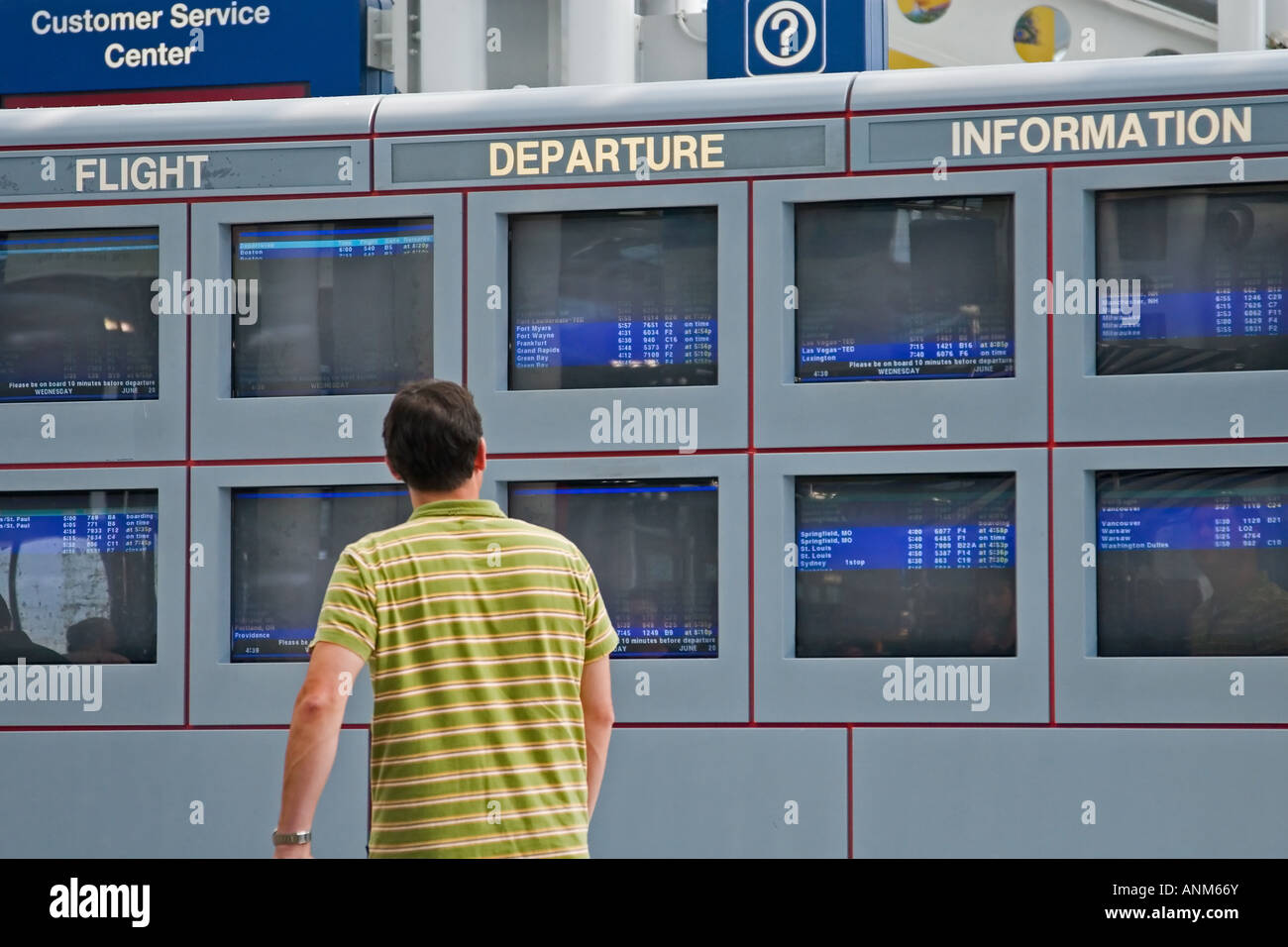 Travellers and businesspeople glance at the departure and arrvial information at an airport for airline schedules Stock Photo