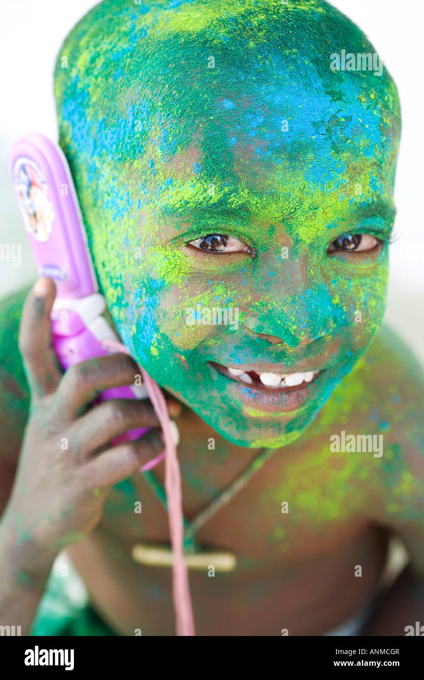 Young Indian boy covered in coloured powder pigment with toy mobile phone. India Stock Photo