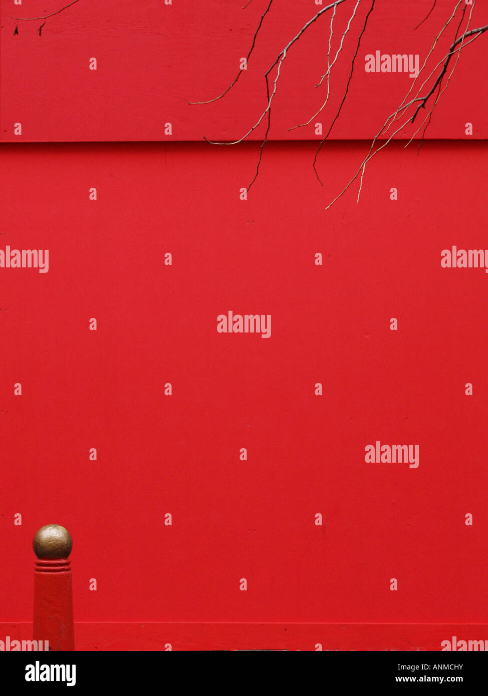 Minimalistic picture of golden globe on a red post against a red wall with branches overhanging, in Chinatown London Stock Photo