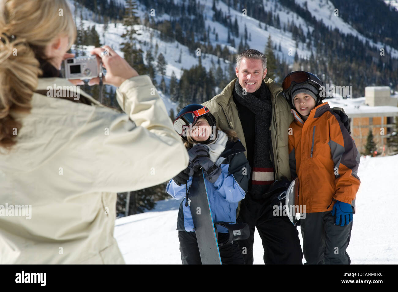 Rear view of a mother taking a photograph of her family with a digital ...