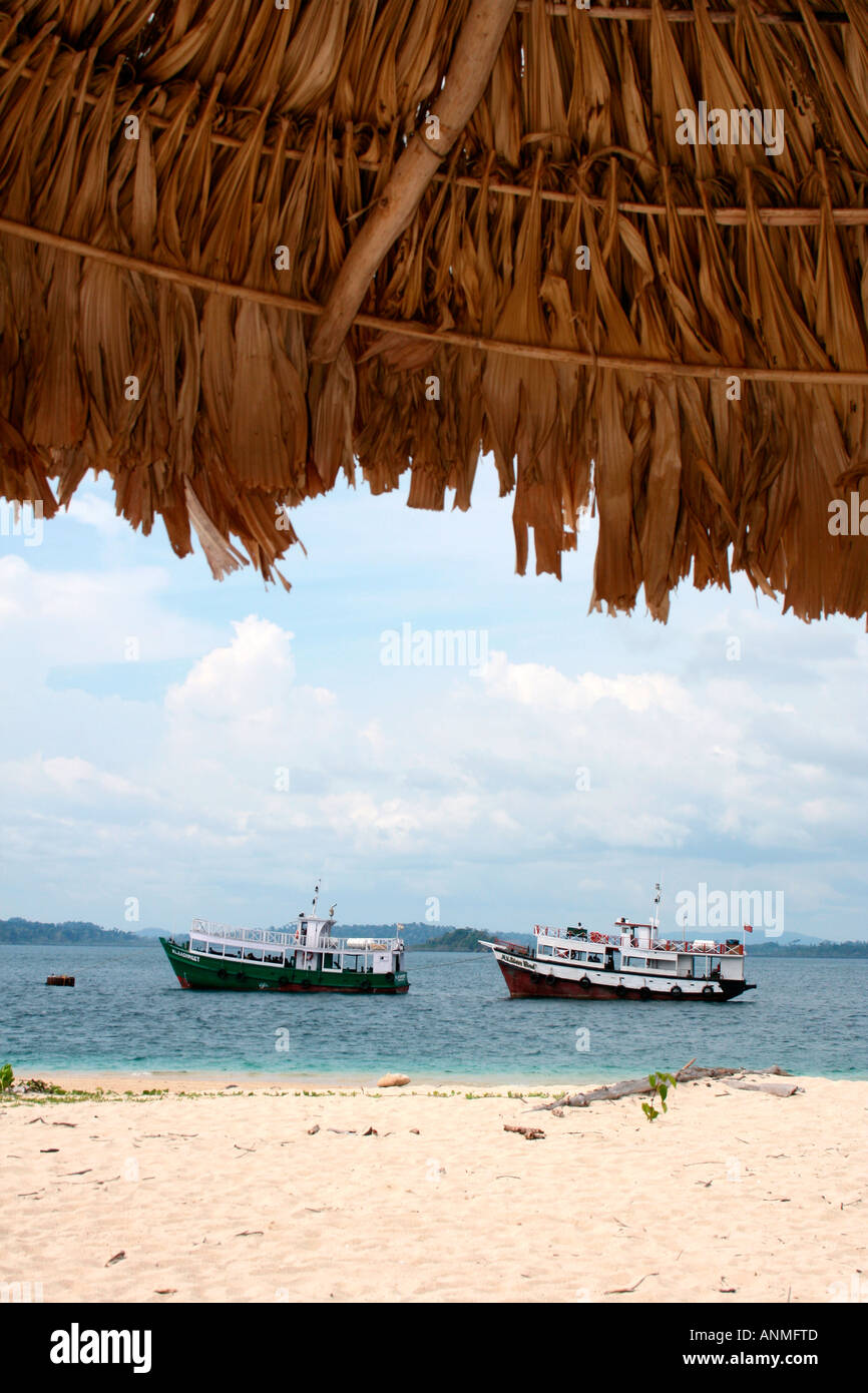 An image of two boats approaching the Jolly buoy beach Andaman bordered on the top by a portion of the hut on the coast Stock Photo