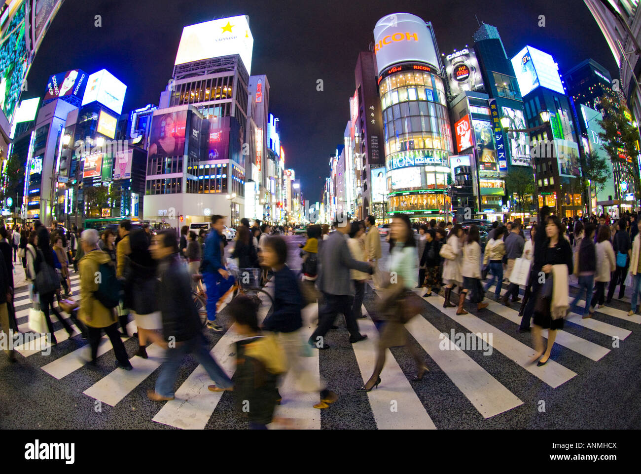 Crowds of pedestrians cross busy street in central Ginza at night Tokyo Stock Photo