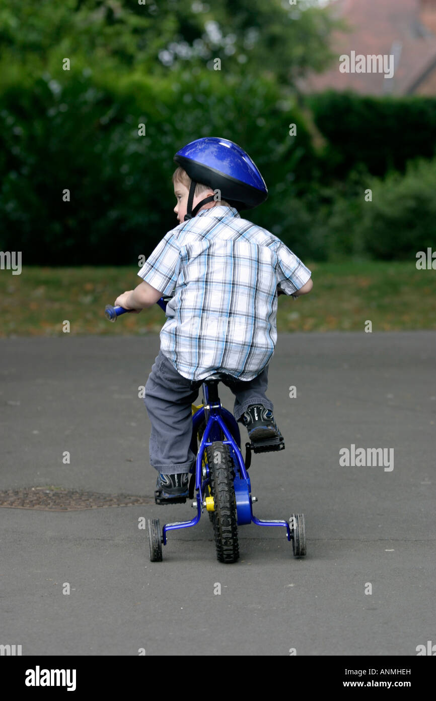six-year-old, riding his bicycle fitted with stabilisers. Arnot Hill Park, Arnold, Nottinghamshire Stock Photo