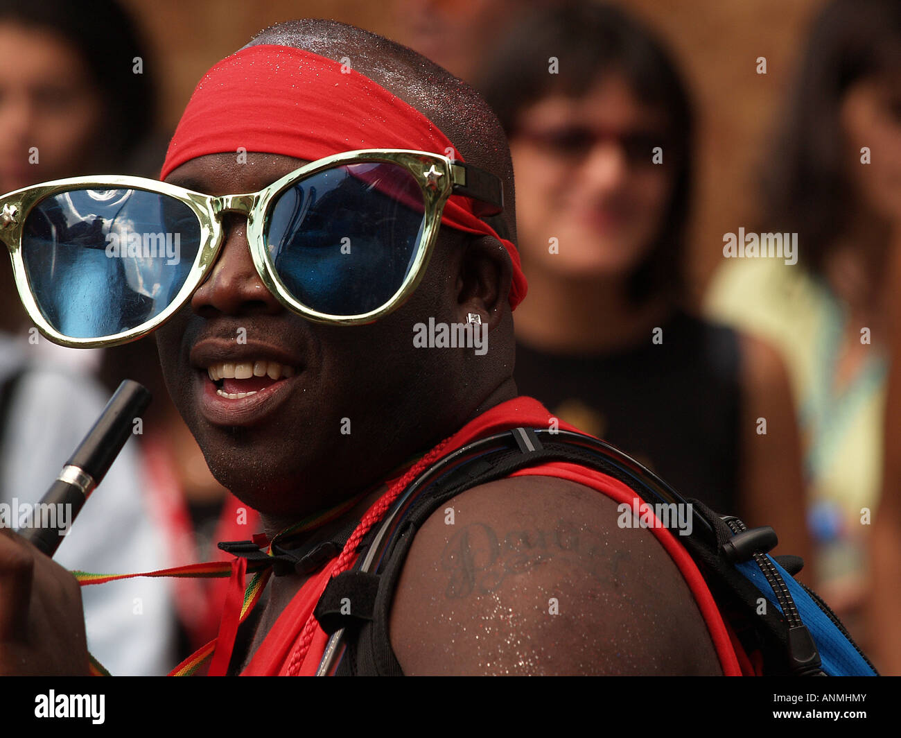 Man in Notting Hill Carnival parade wearing novelty oversized glasses and smiling. Editorial use only. Stock Photo