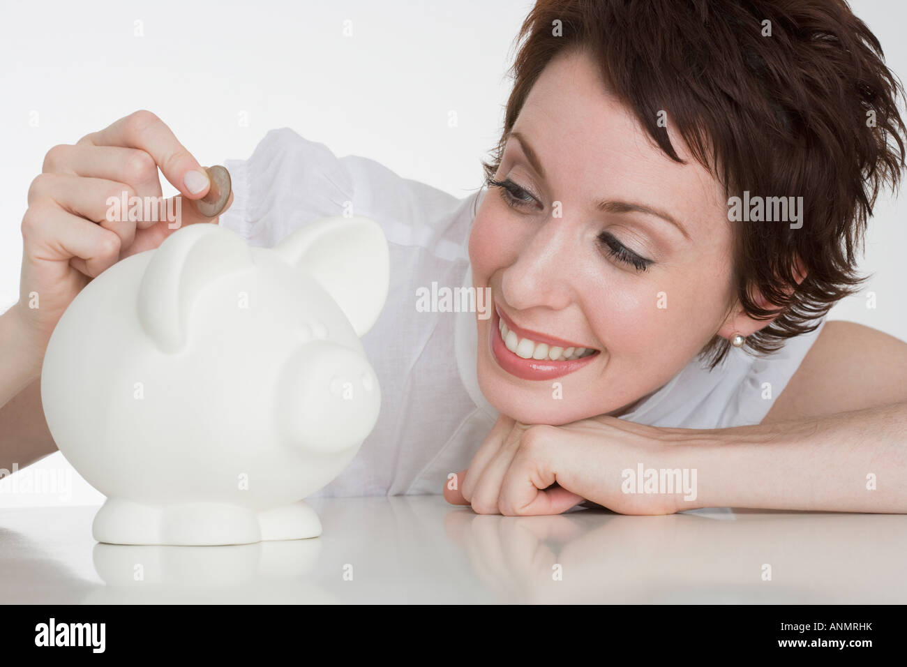 Woman putting coin in piggy bank Stock Photo - Alamy
