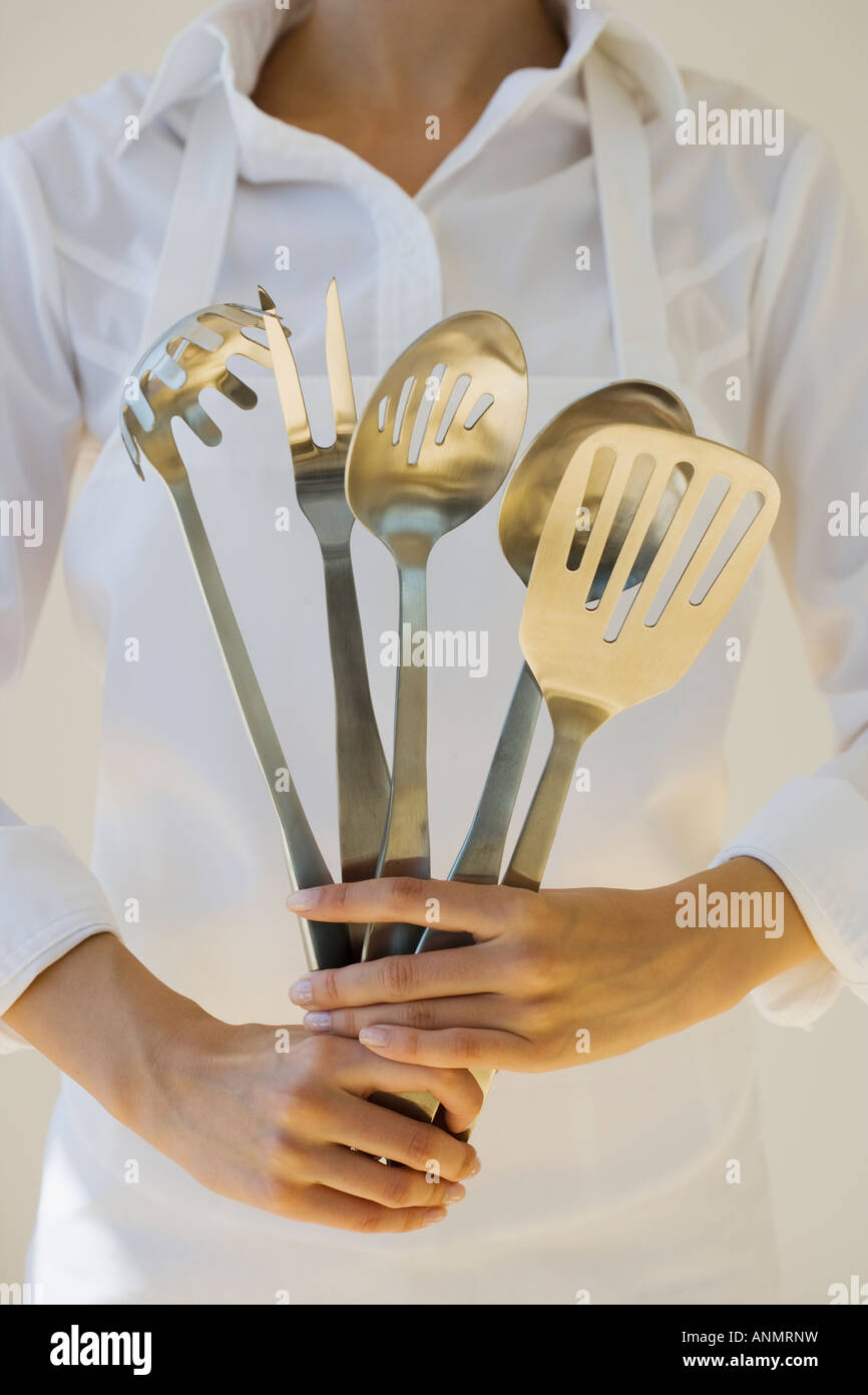 Woman holding assorted serving utensils Stock Photo
