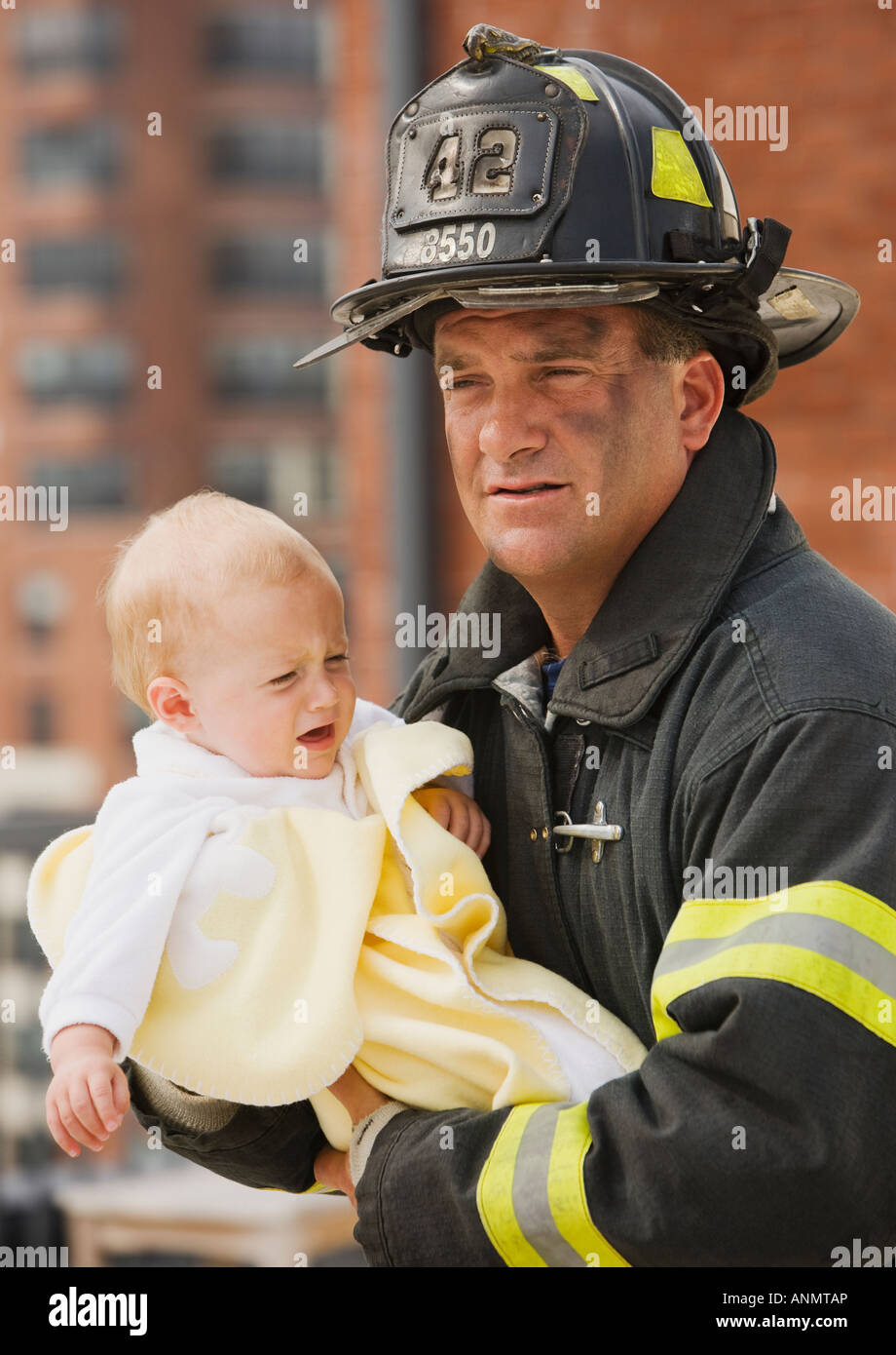 Male firefighter carrying baby Stock Photo