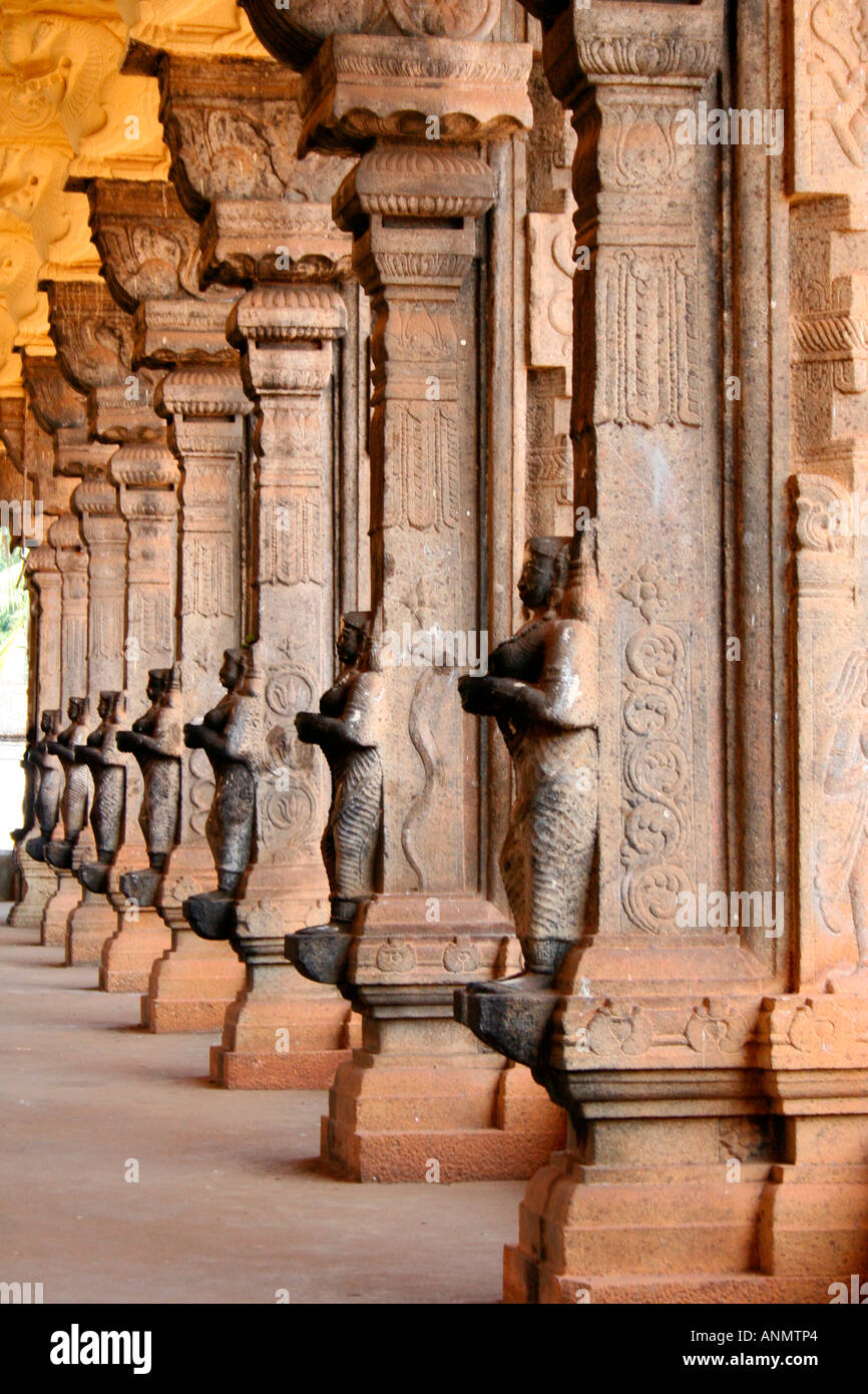 Close up of the stone pillars with sculptures lining the side of a long passage in a temple in
