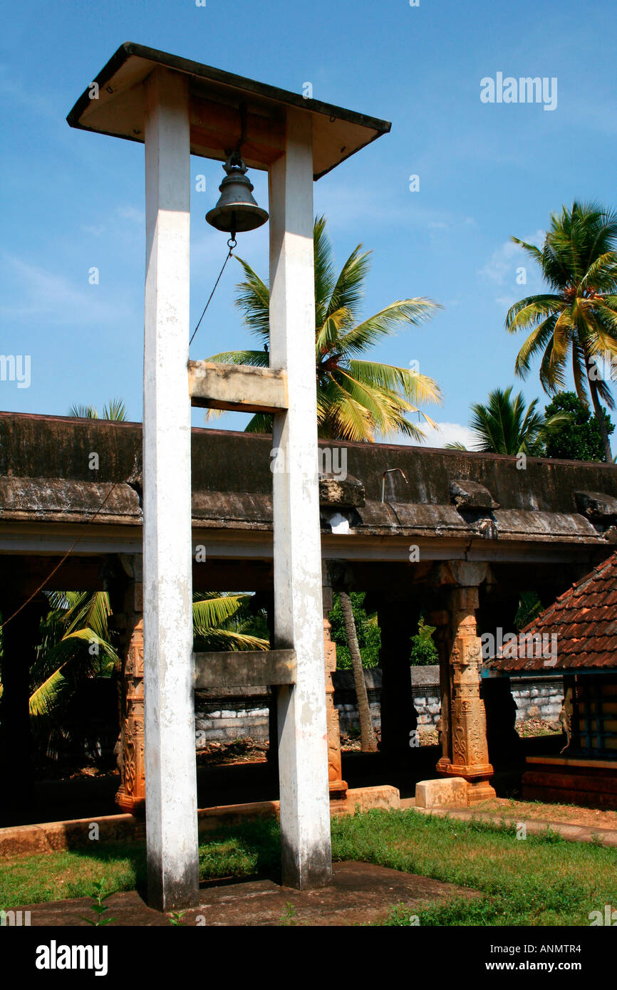 A bell hanging on a tall structure and portion of the walkway and premises in a temple in Tamil Nadu Stock Photo