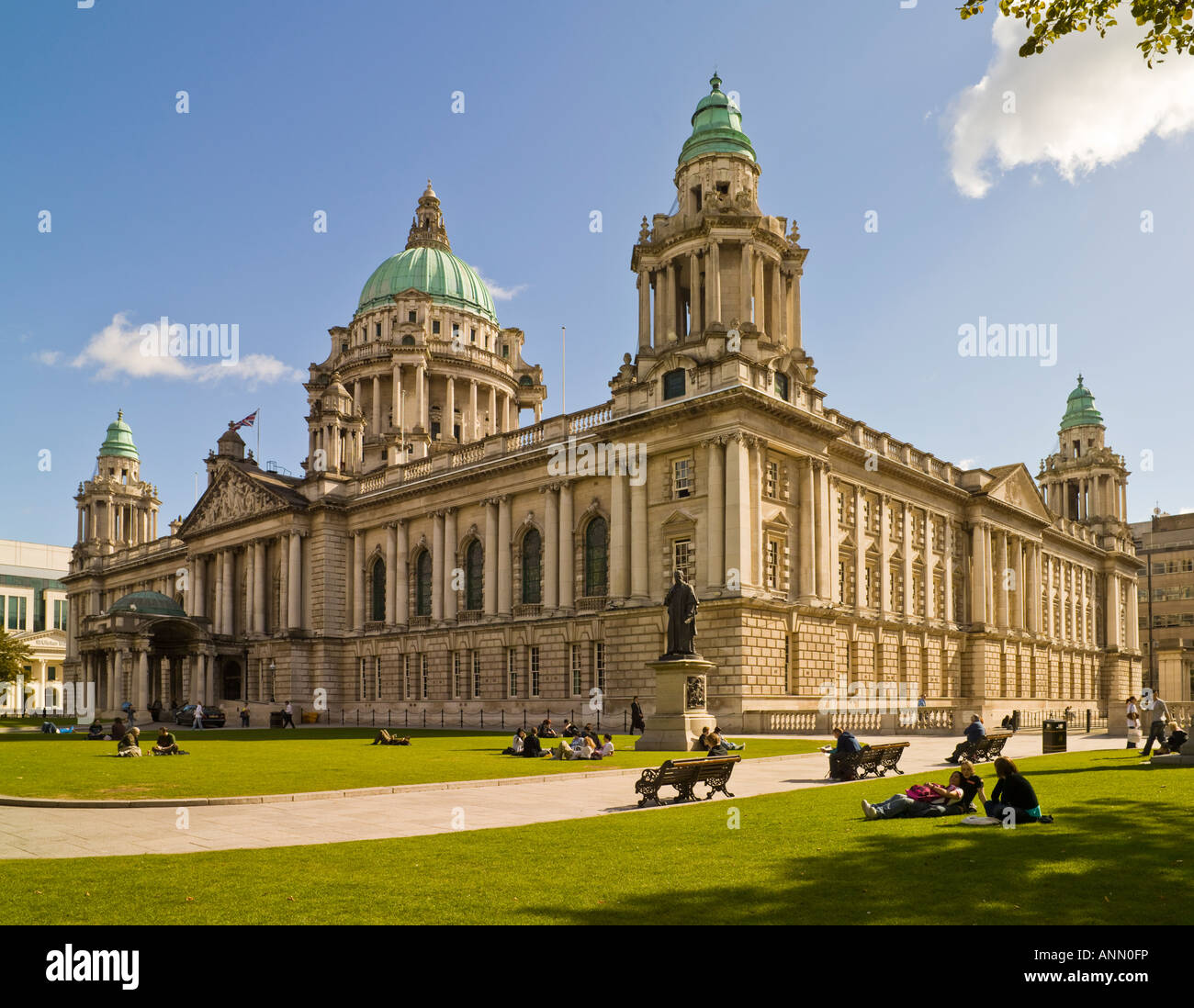 Grand Edwardian Baroque architecture of Belfast City Hall in Northern Ireland, featuring a large dome and ornate details, surrounded by manicured lawns, illuminated at dusk.