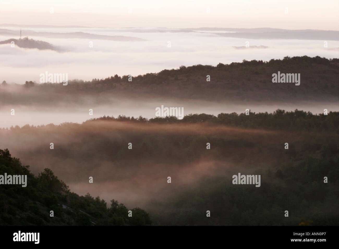 Valley mist and wooded slopes and rolling hills at daybreak Stock Photo