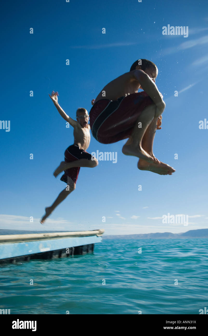 Brothers jumping off dock into lake, Utah, United States Stock Photo