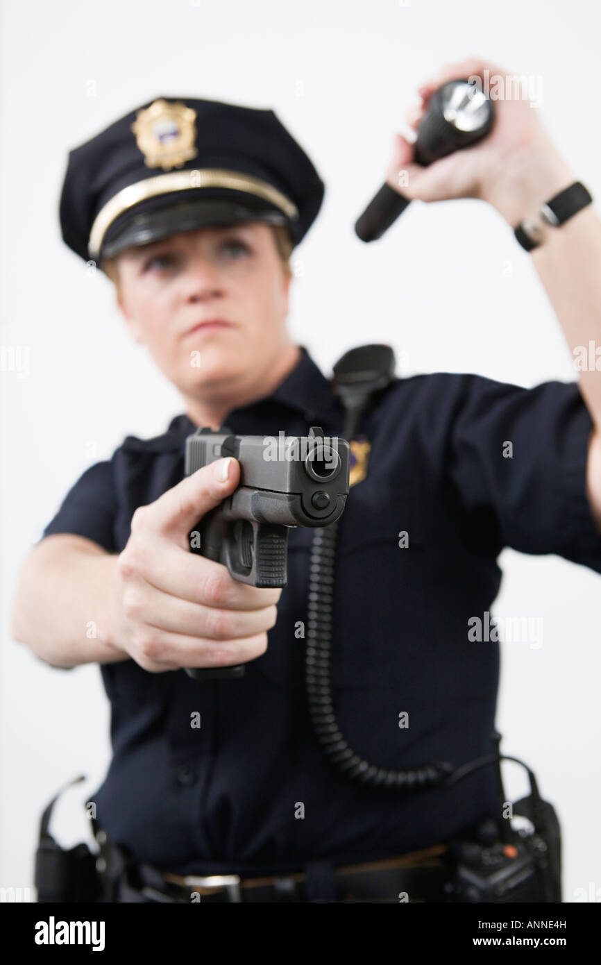 Police woman pointing handgun and holding flashlight. Stock Photo
