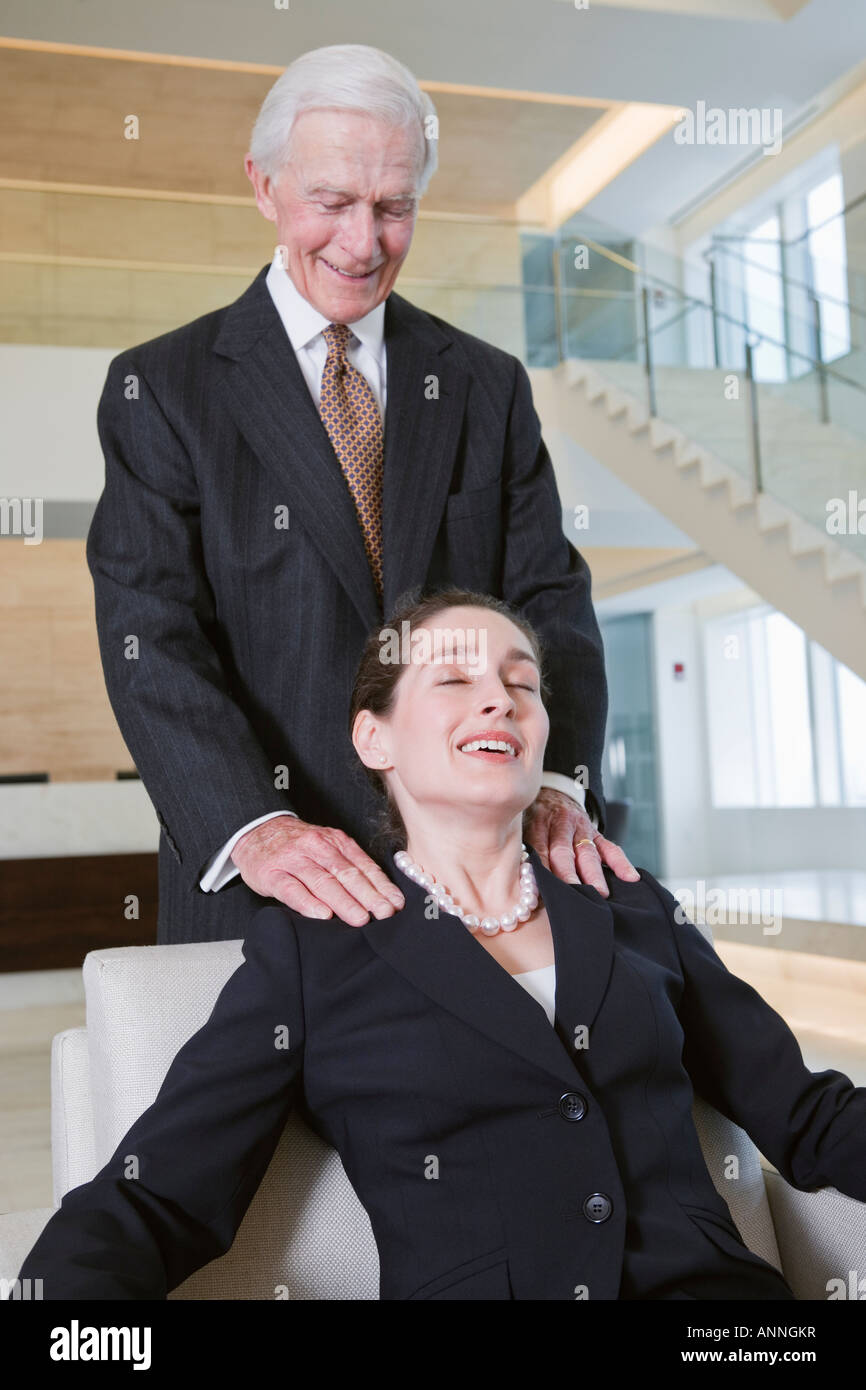 View of businessman giving shoulder massage to executive in an office. Stock Photo
